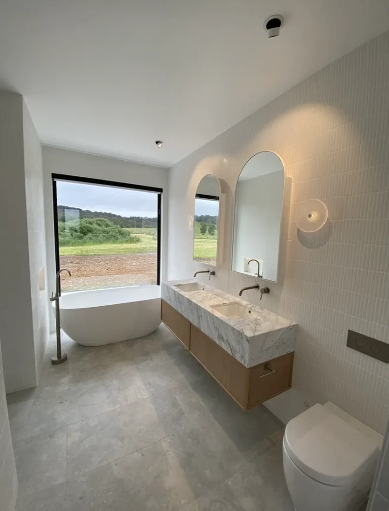 Modern bathroom with bathtub and two sinks.
