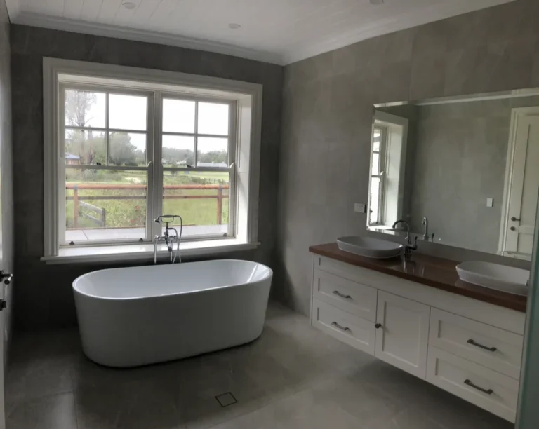 Modern bathroom with bathtub and double sinks.