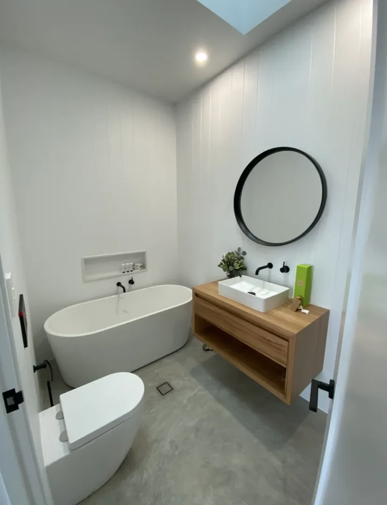 Modern bathroom with tub, sink, mirror, and toilet.