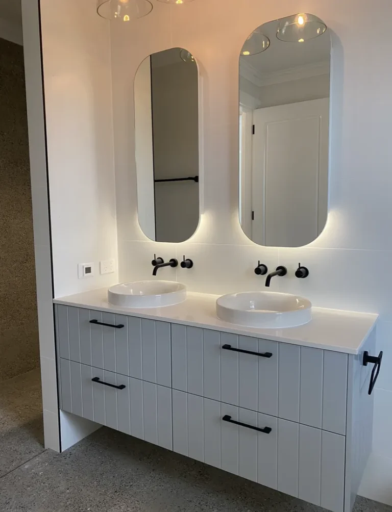 Modern bathroom vanity with dual sinks and mirrors.