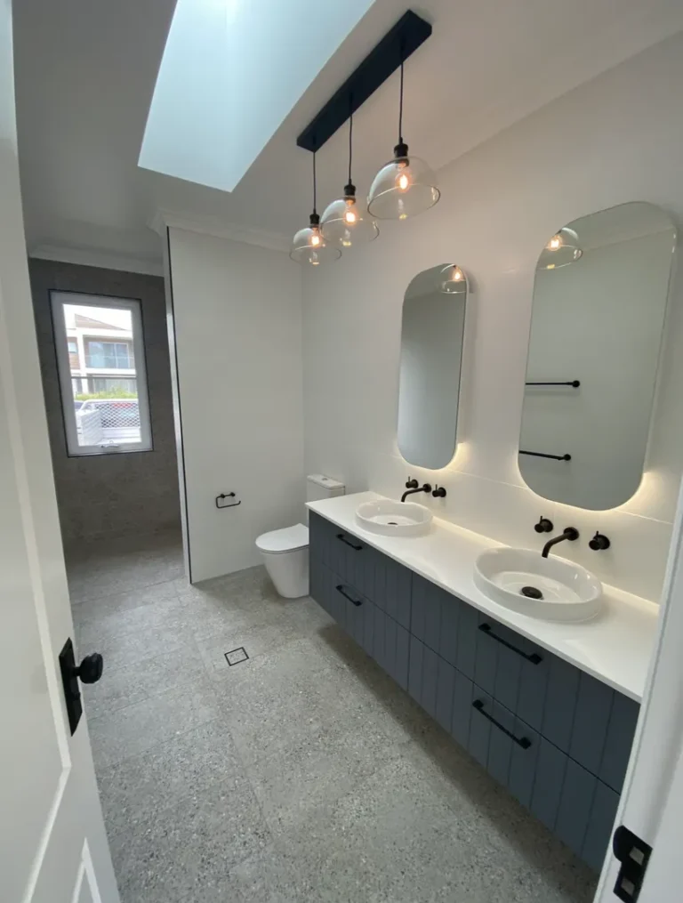 Modern bathroom with double sinks and hanging lights.