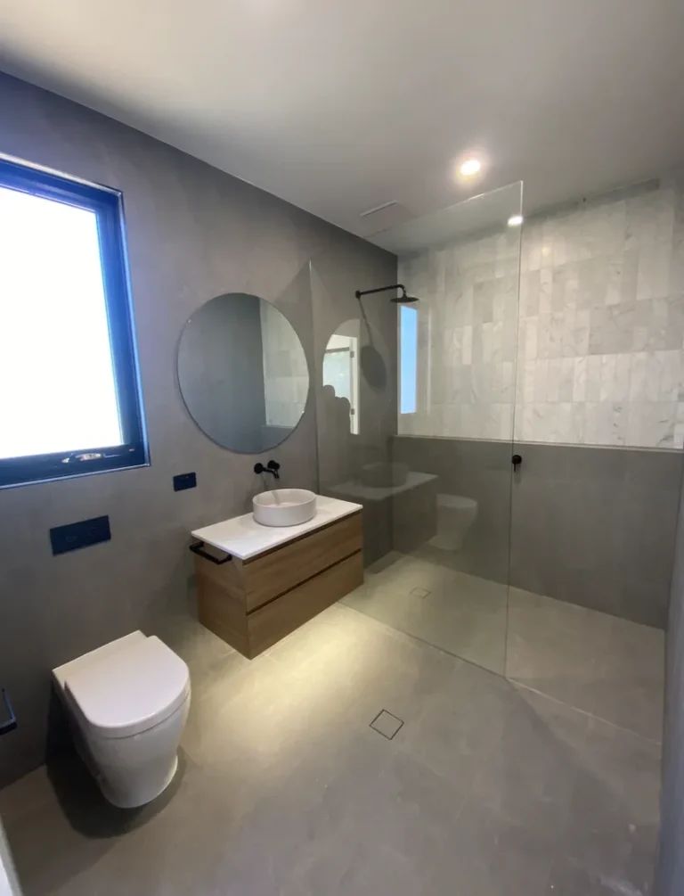 Modern bathroom with glass shower, toilet, and vanity.