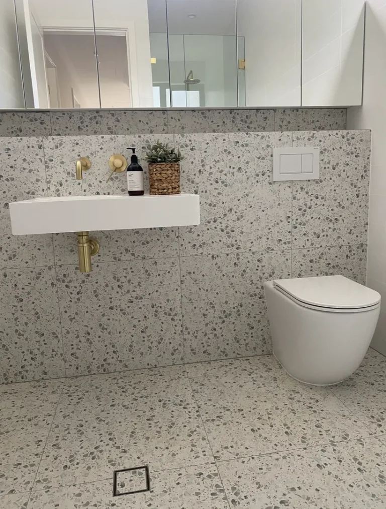 Modern bathroom with terrazzo tiles and gold fixtures.