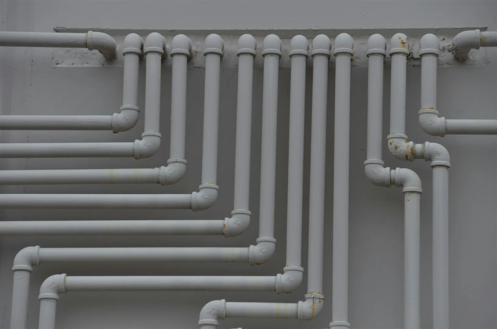 White interconnected pipes on gray wall